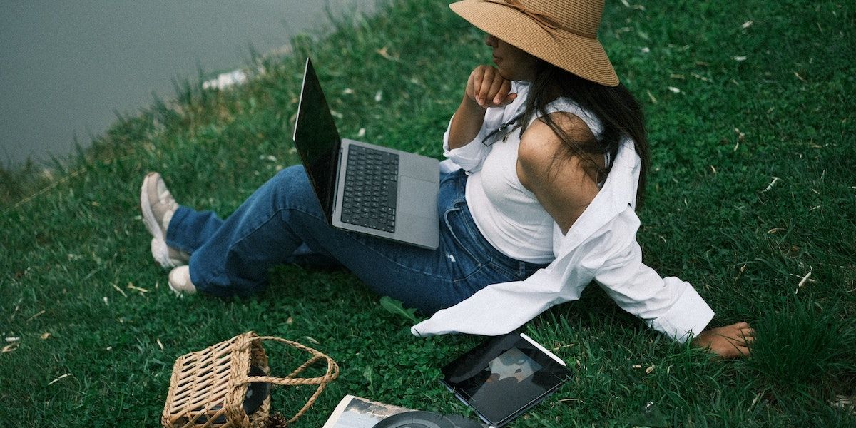 mulher sentada à beira do lago analisando dados com laptop