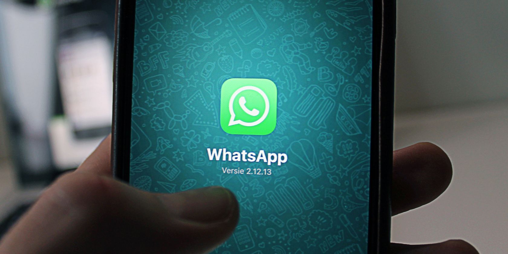 A man holding a smartphone displaying the WhatsApp logo on the screen