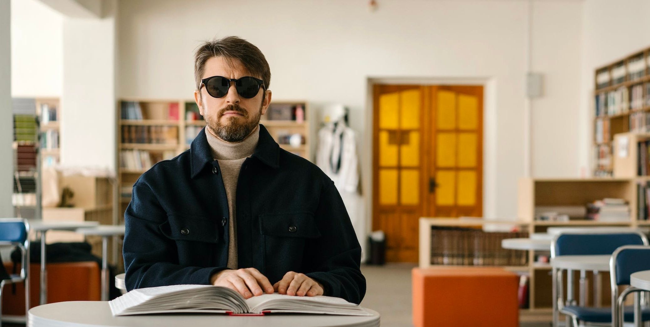 A man wearing sunglasses touching an open book