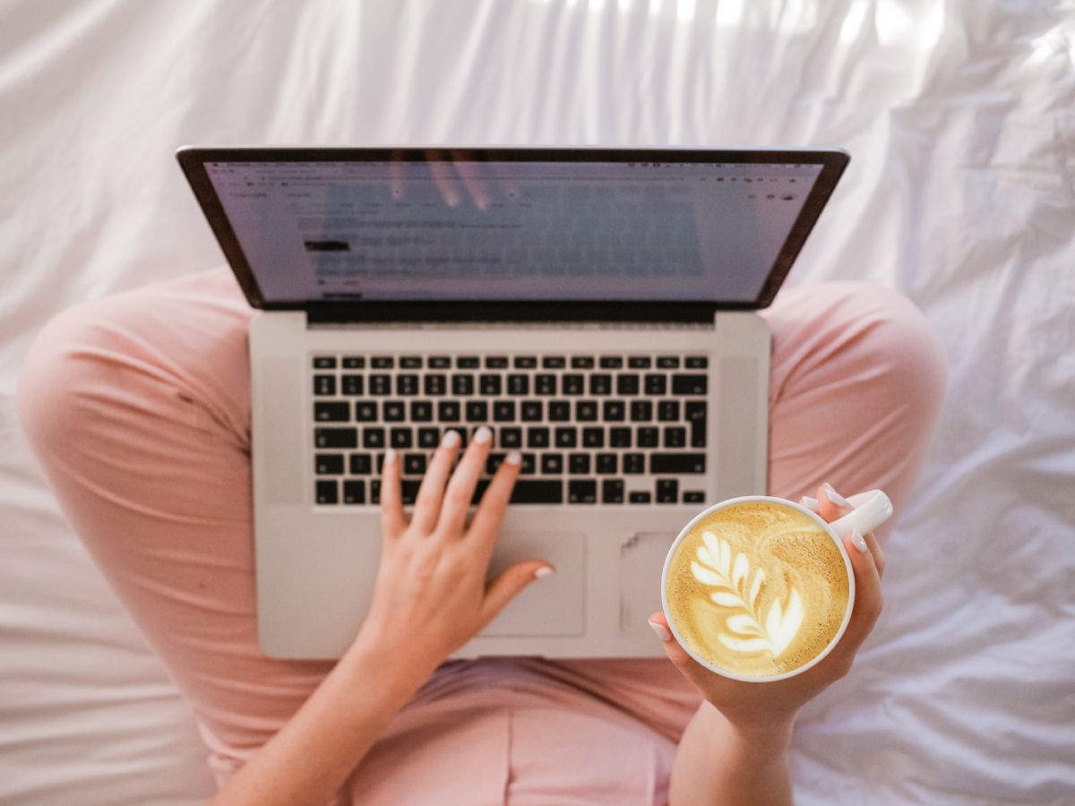 O persoană care citește pe laptop și ține o ceașcă de cafea