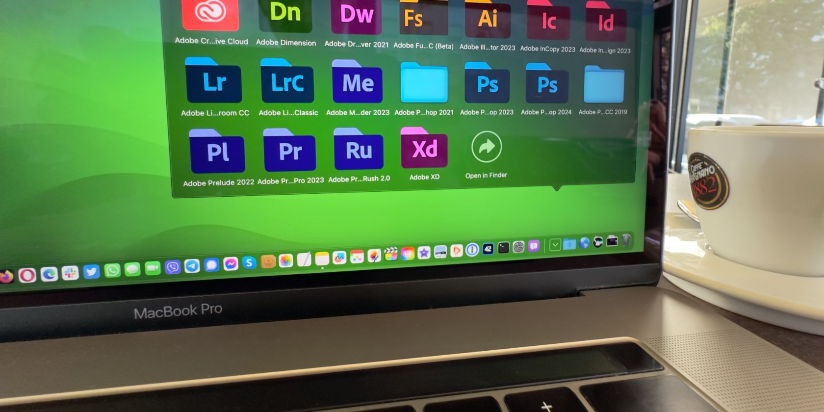 MacBook Pro showing a folder of Adobe apps in the Dock