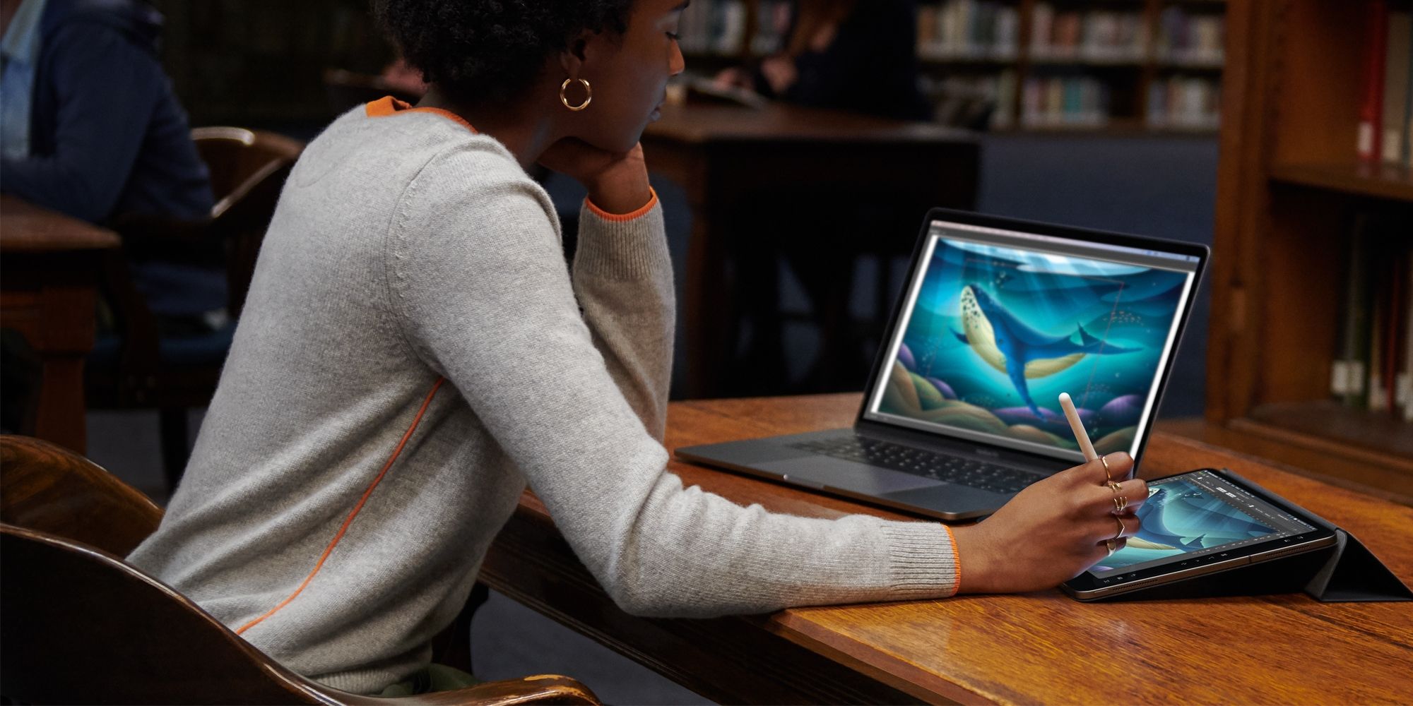 Seorang wanita menggunakan fitur Sidecar Apple untuk menggunakan iPad dan Apple Pencil miliknya untuk menggambar di aplikasi Mac