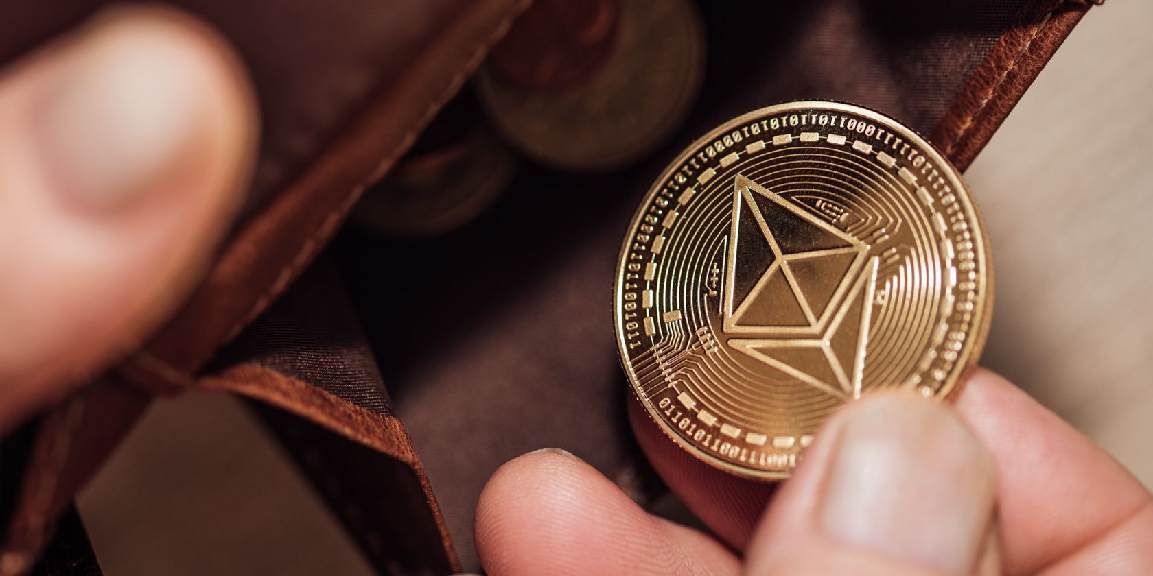 close up shot of person taking ethereum coin out of leather wallet