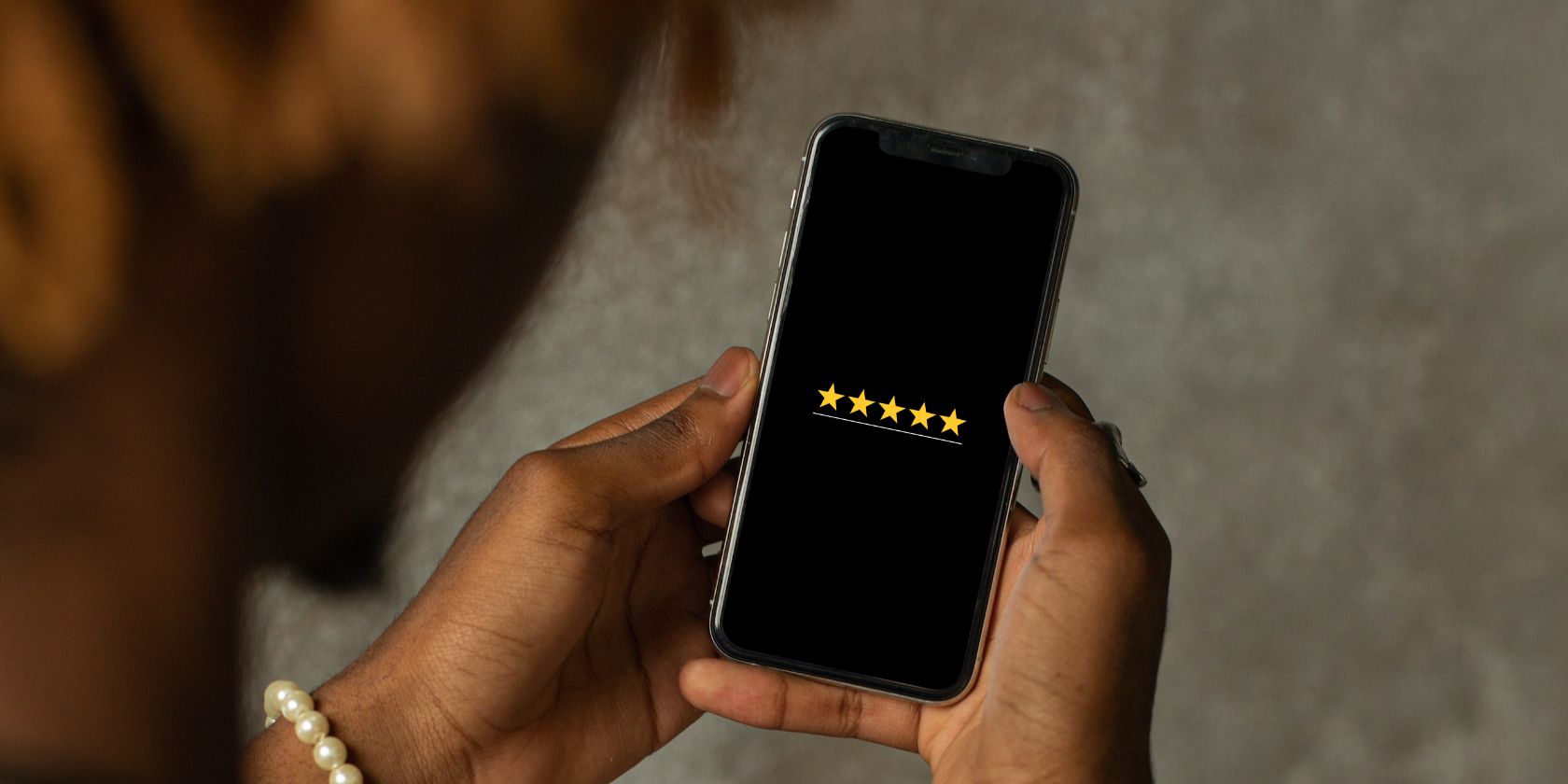 Man holding an iPhone with 5 gold stars on screen