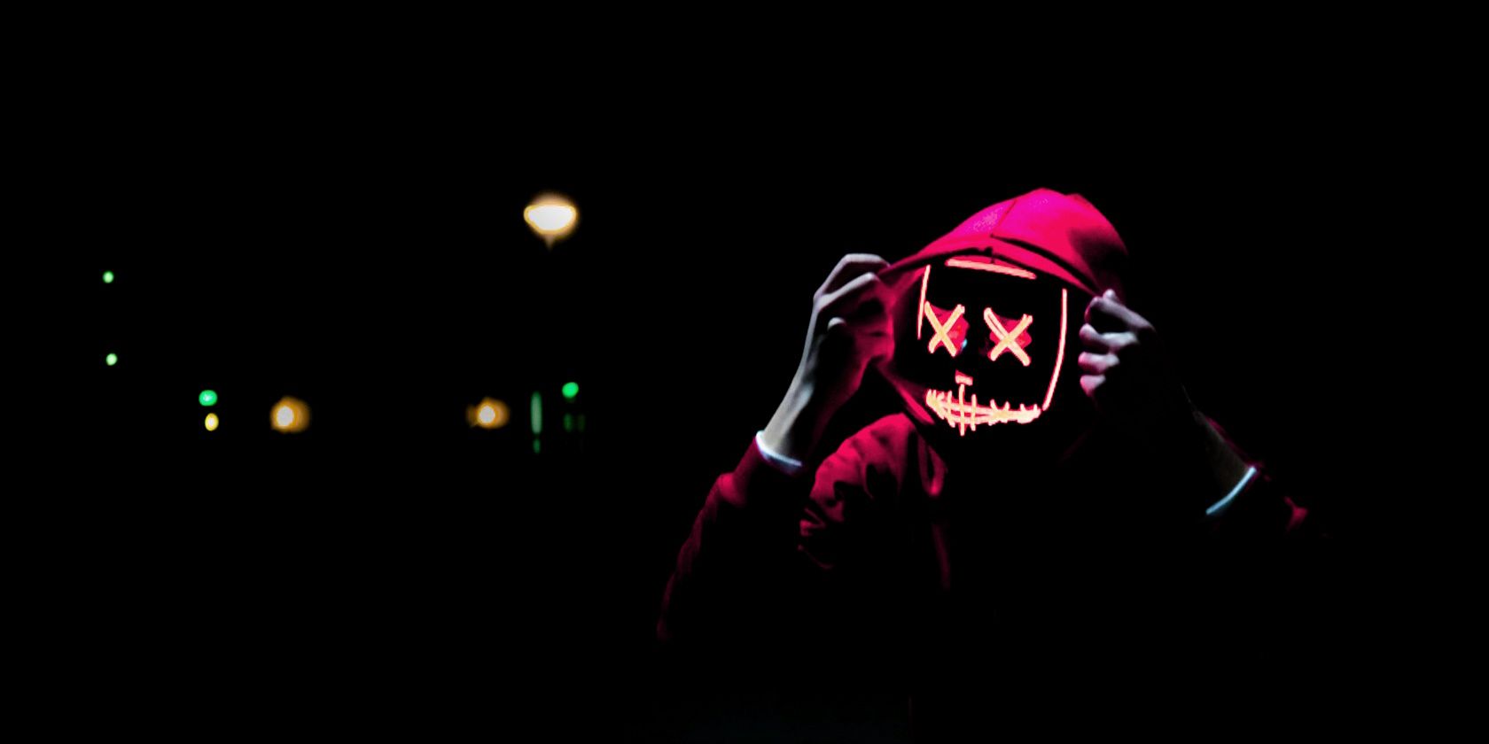 Person wearing hoodie and a neon mask