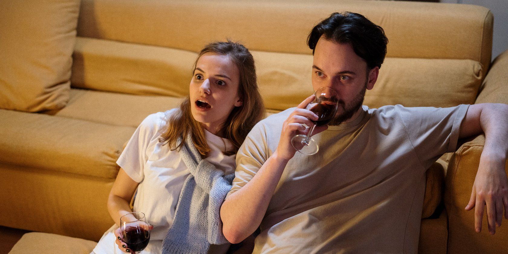 Shocked couple watching TV with wine