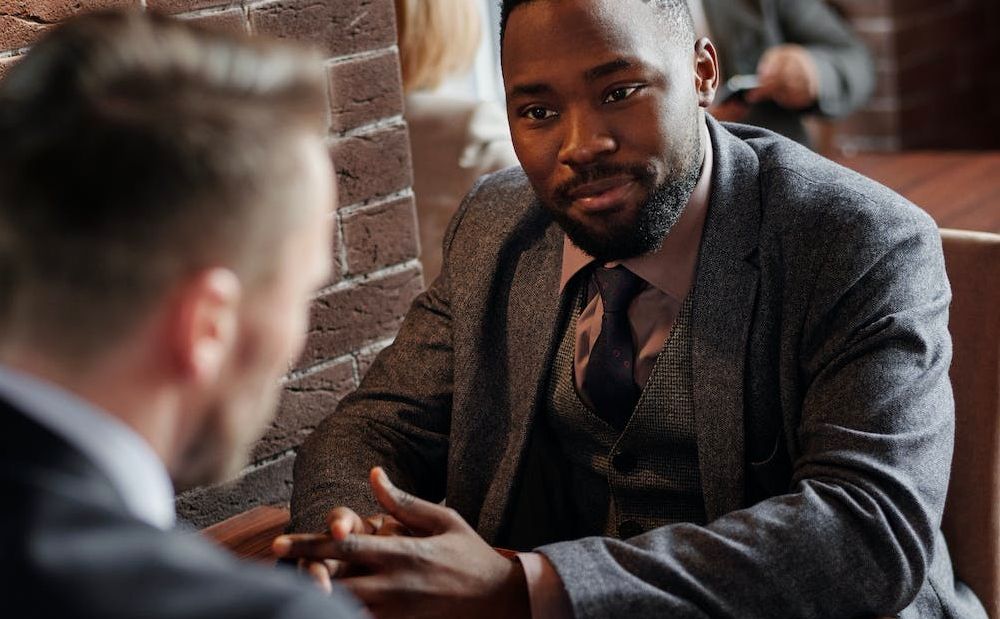 Duas pessoas de terno sentadas à mesa