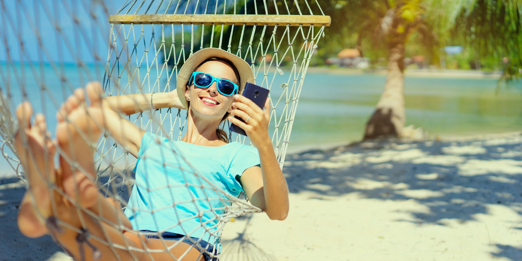 woman in hammock using smartphone on holiday