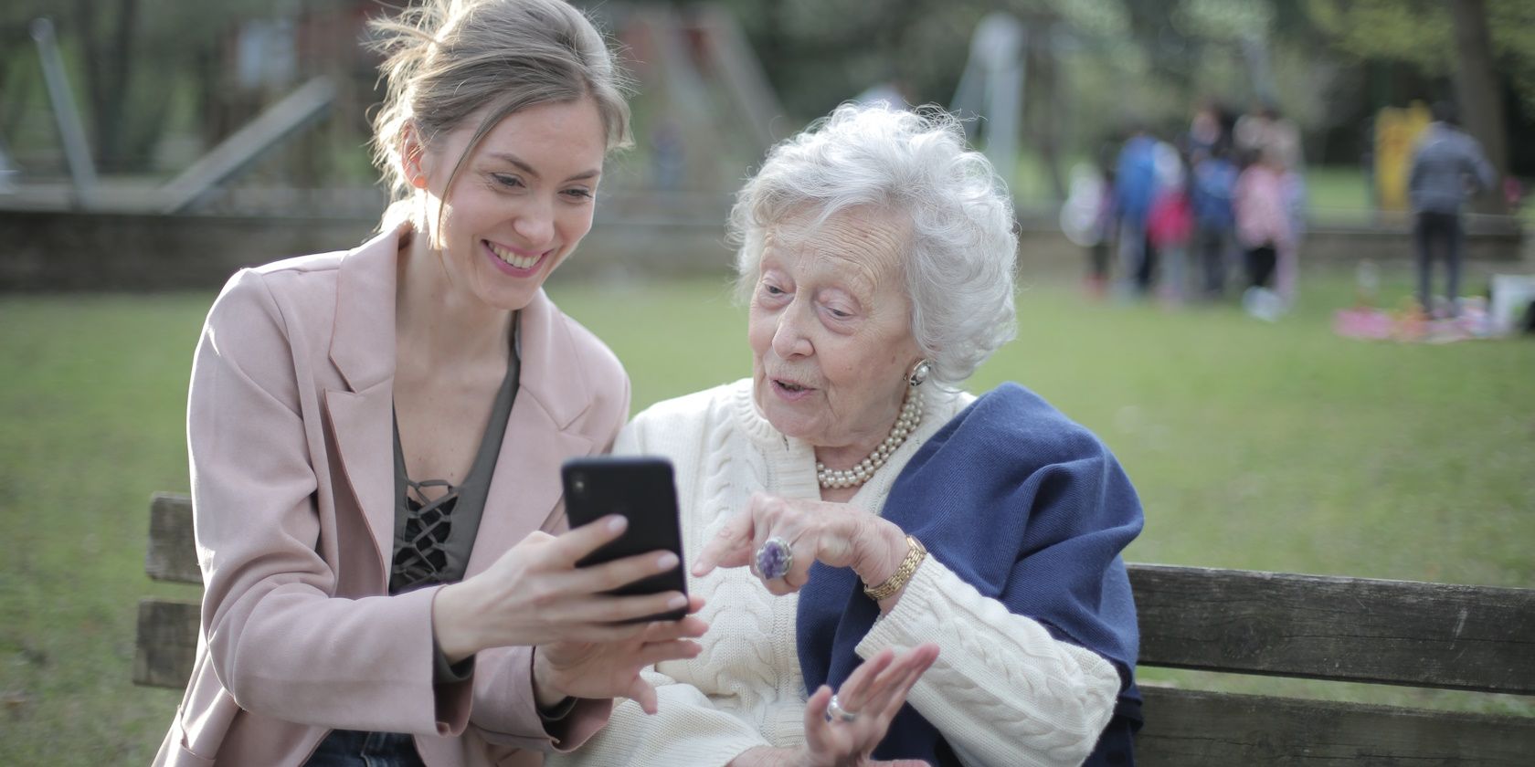 happy young woman and senior woman looking at smartphone