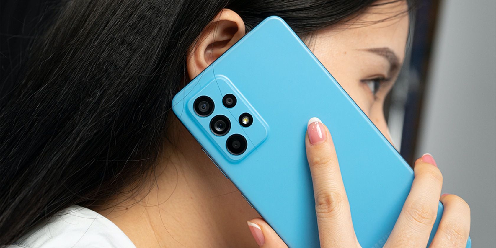 A woman holding a cyan blue Android phone.