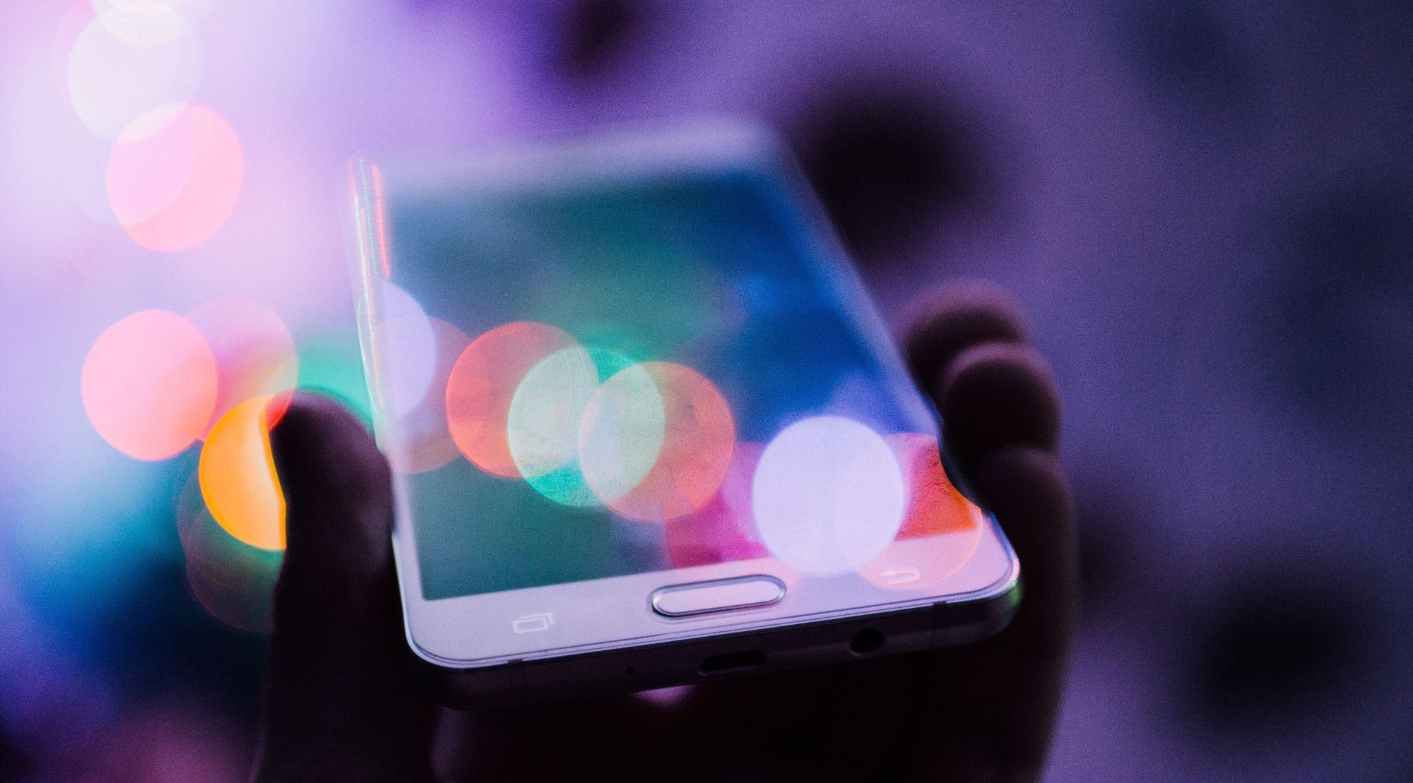 person holding smartphone with blurred light hue outside