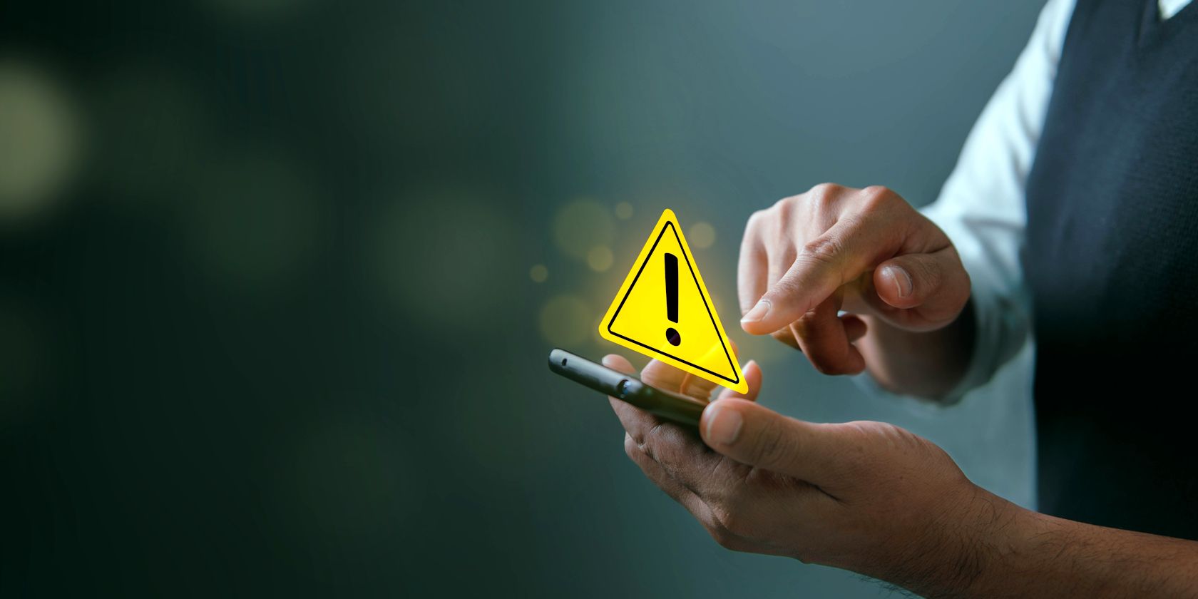 man using smartphone with yellow warning sign pop up