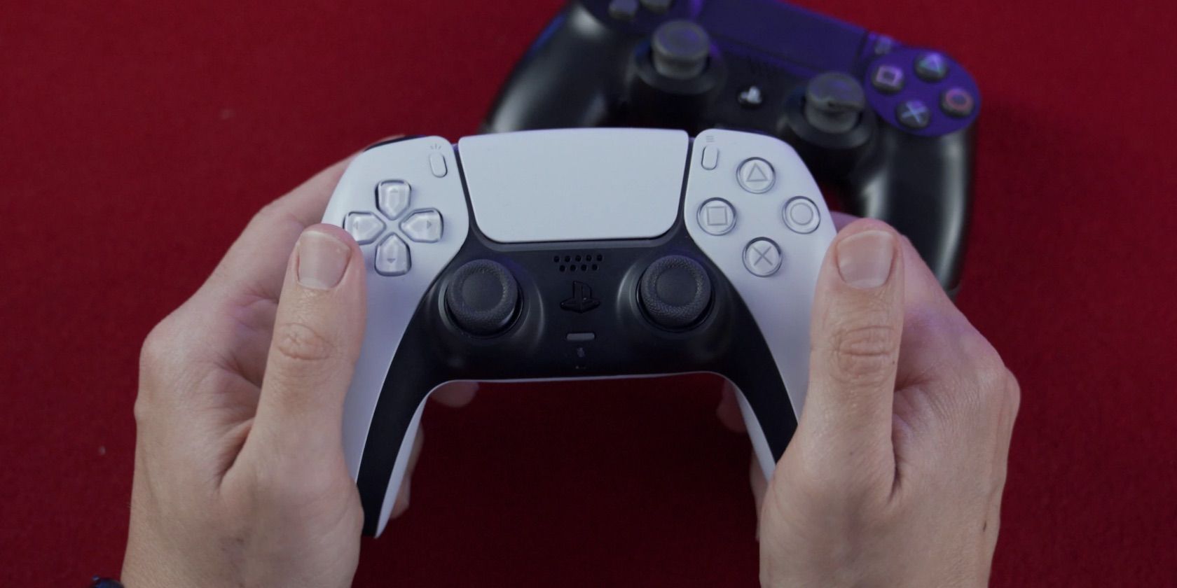 شخصی که کنترلر DualSense را با کنترلر PS4 روی پس زمینه قرمز در دست دارد