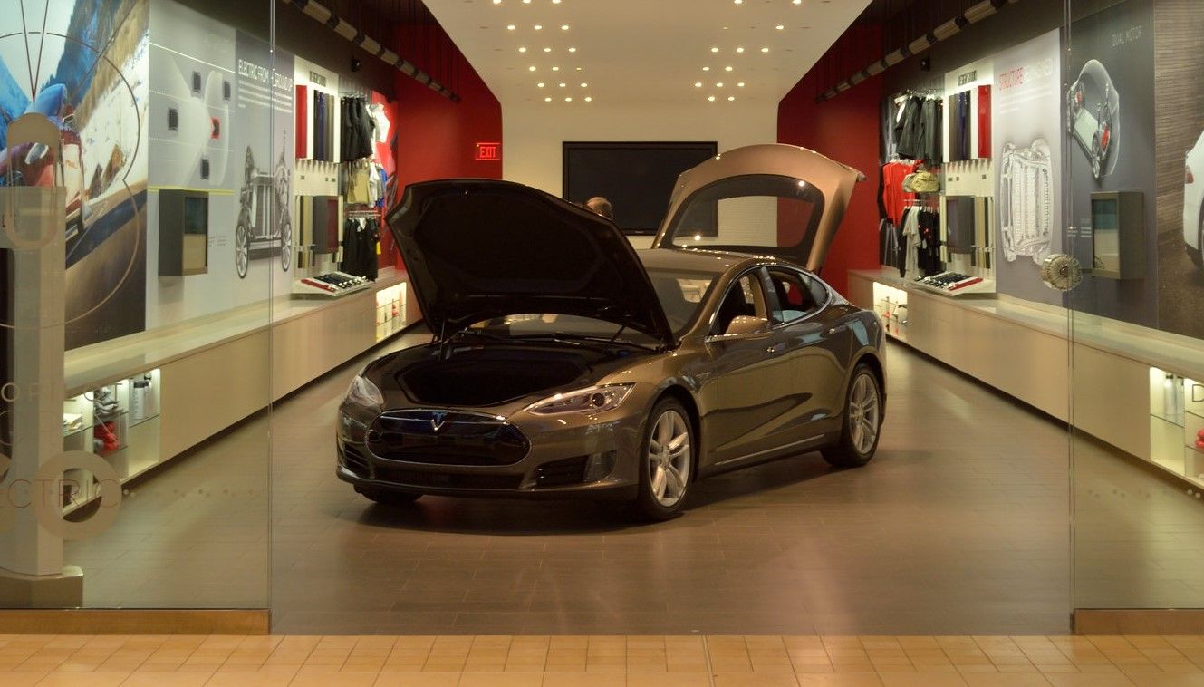 tesla car in middle of shop with hood and trunk open