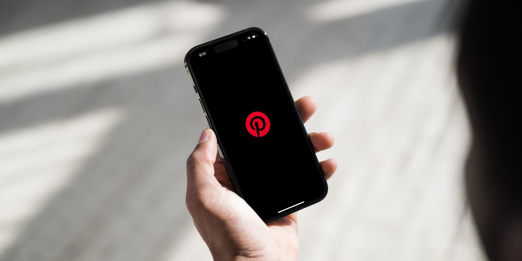 Phone in a hand with Pinterest icon on the screen and dark mode enabled 