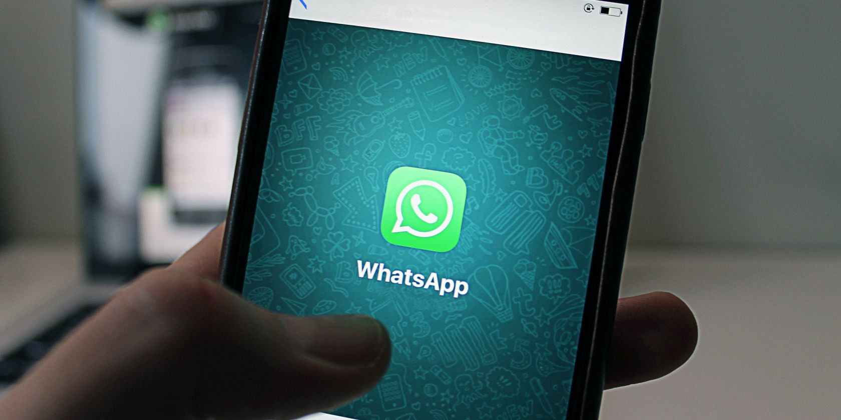 Hand holding phone with WhatsApp logo
