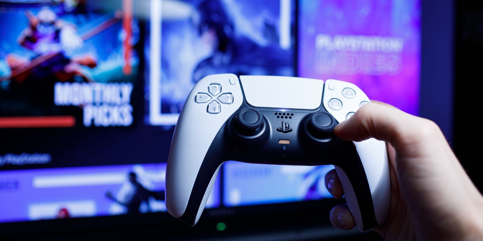 a ps5 controller held in front of a TV screen