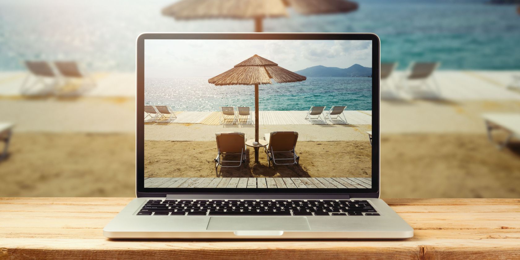Laptop on a bench at the beach, showing beach view as the wallpaper