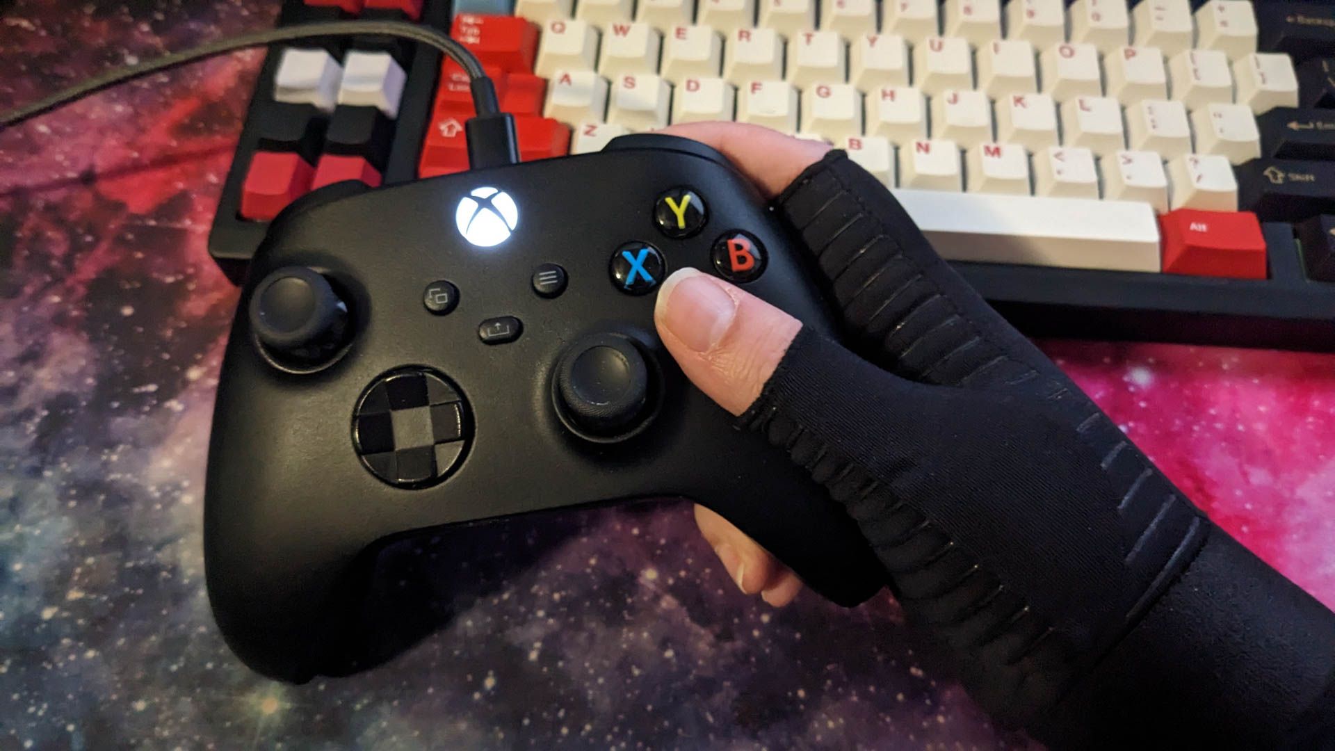 A person wearing gaming gloves and holding an Xbox controller.