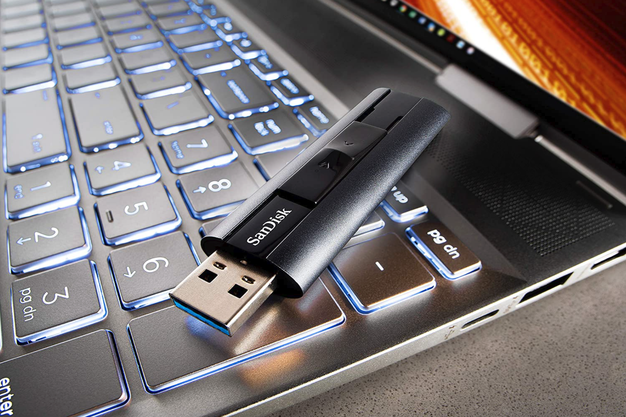 A SanDisk Extreme Pro USB 3.2 resting on a laptop