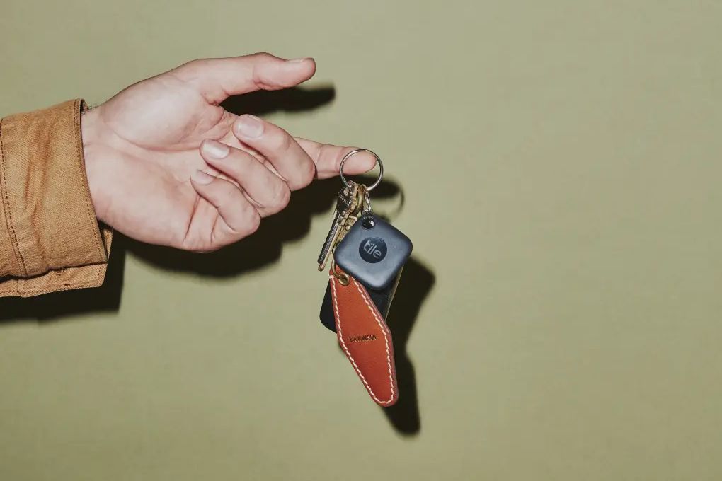 a hand holds a tile mate attached to a keyring