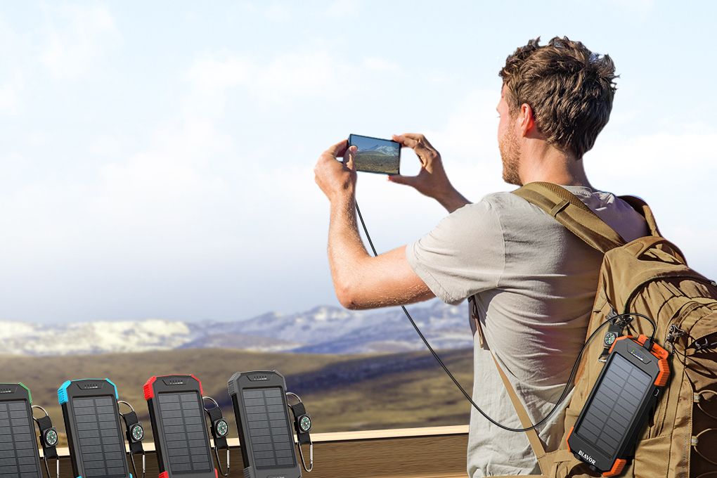 a man charges his blavor qi wireless solar power banks while photographing a mountain range