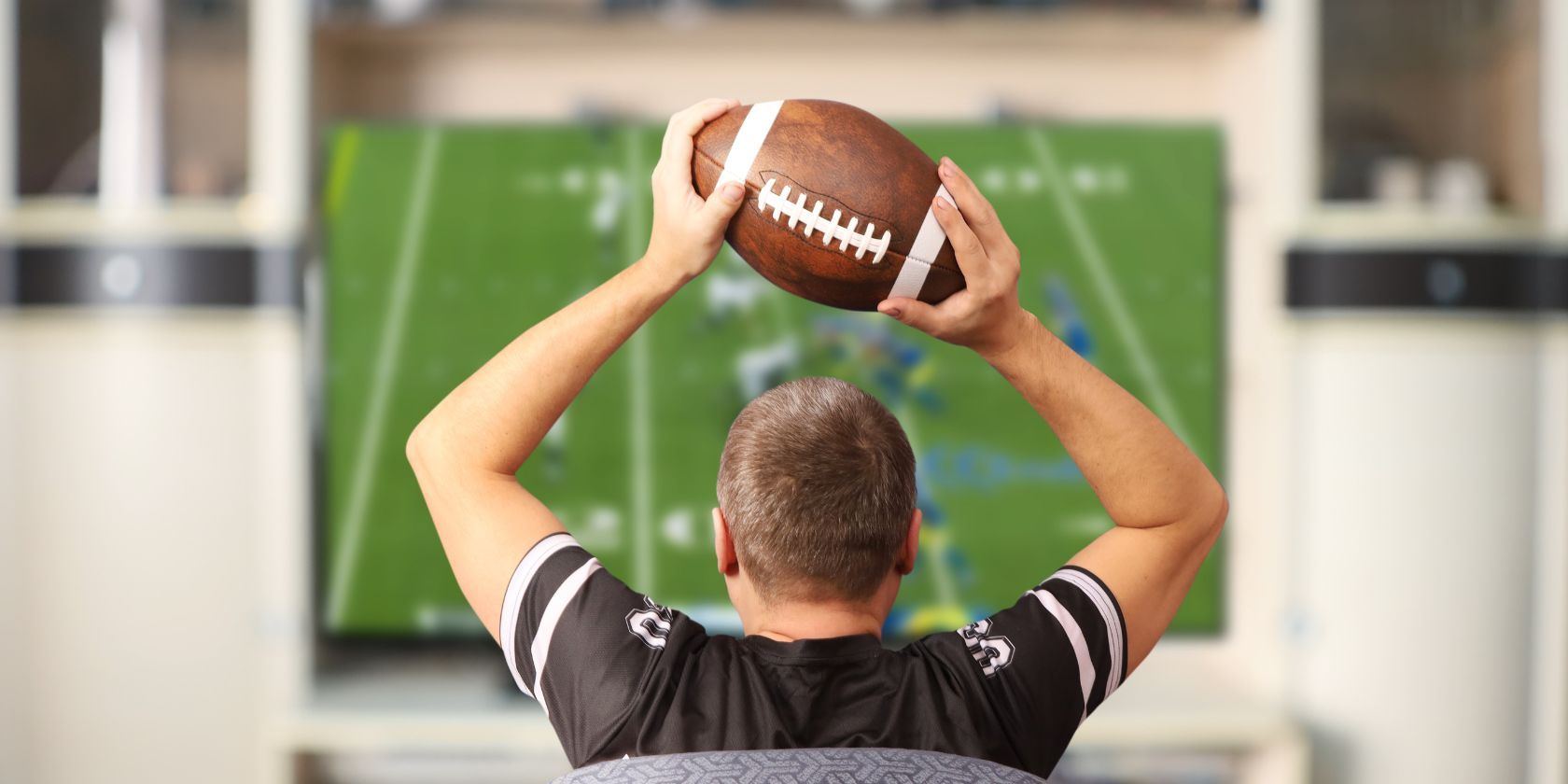 a man watching american football with a football in his hands