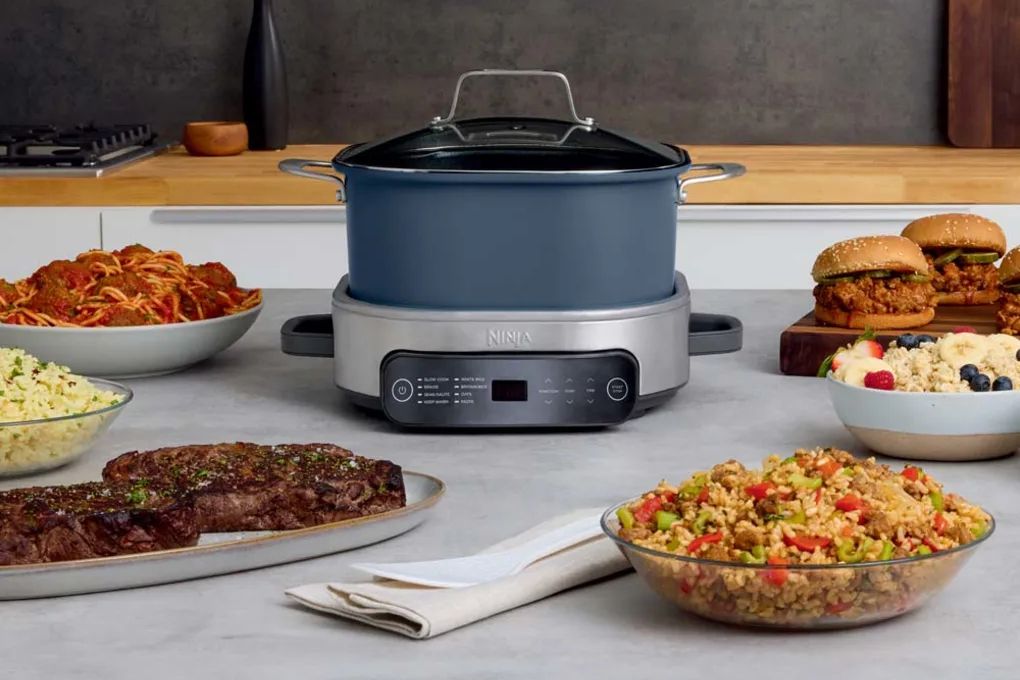 a ninja foodi everyday possiblecooker pro sits in the middle of delicious cooked dishes