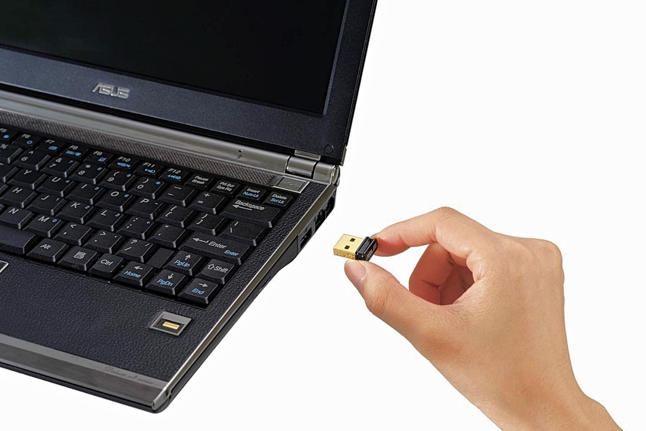 O mână pe cale să conecteze un adaptor Bluetooth Asus BT500 la un laptop.