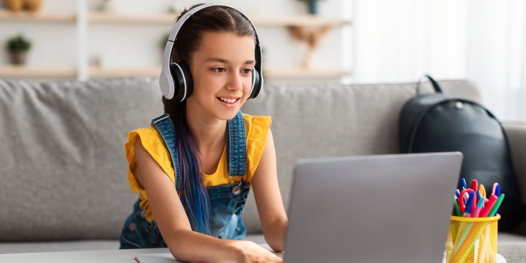 Girl playing on laptop wearing headphones