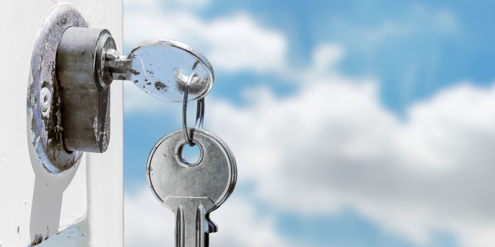 Keys inserted into a lock with sky background