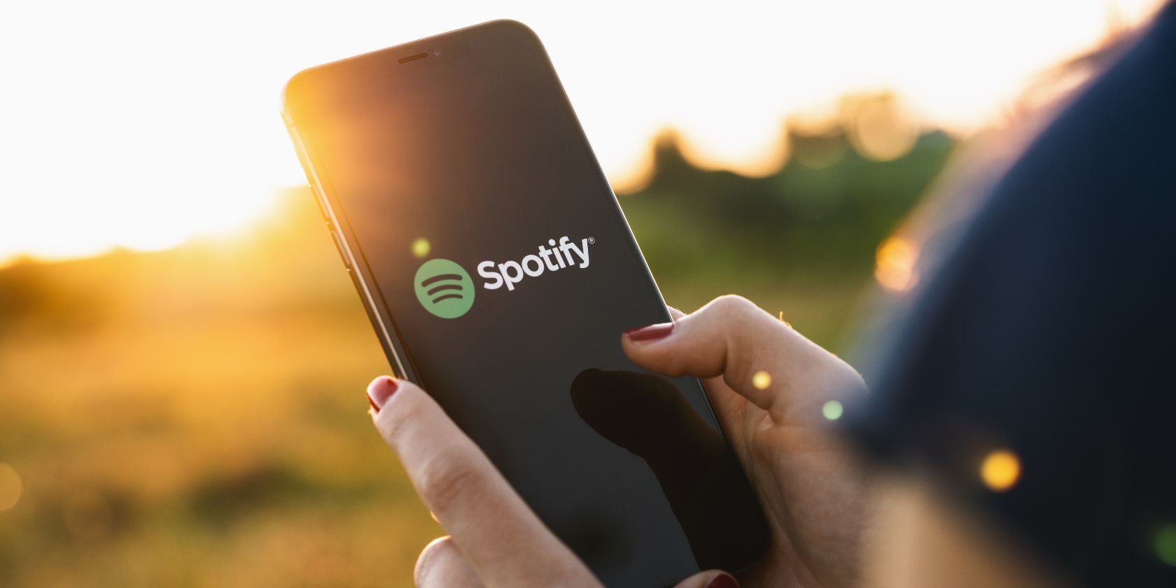 spotify logo on a smartphone with sunset in background