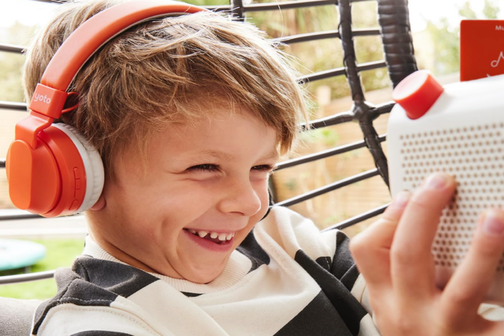 A boy laughing while listening to Yoto Player (3rd generation) on headphones.