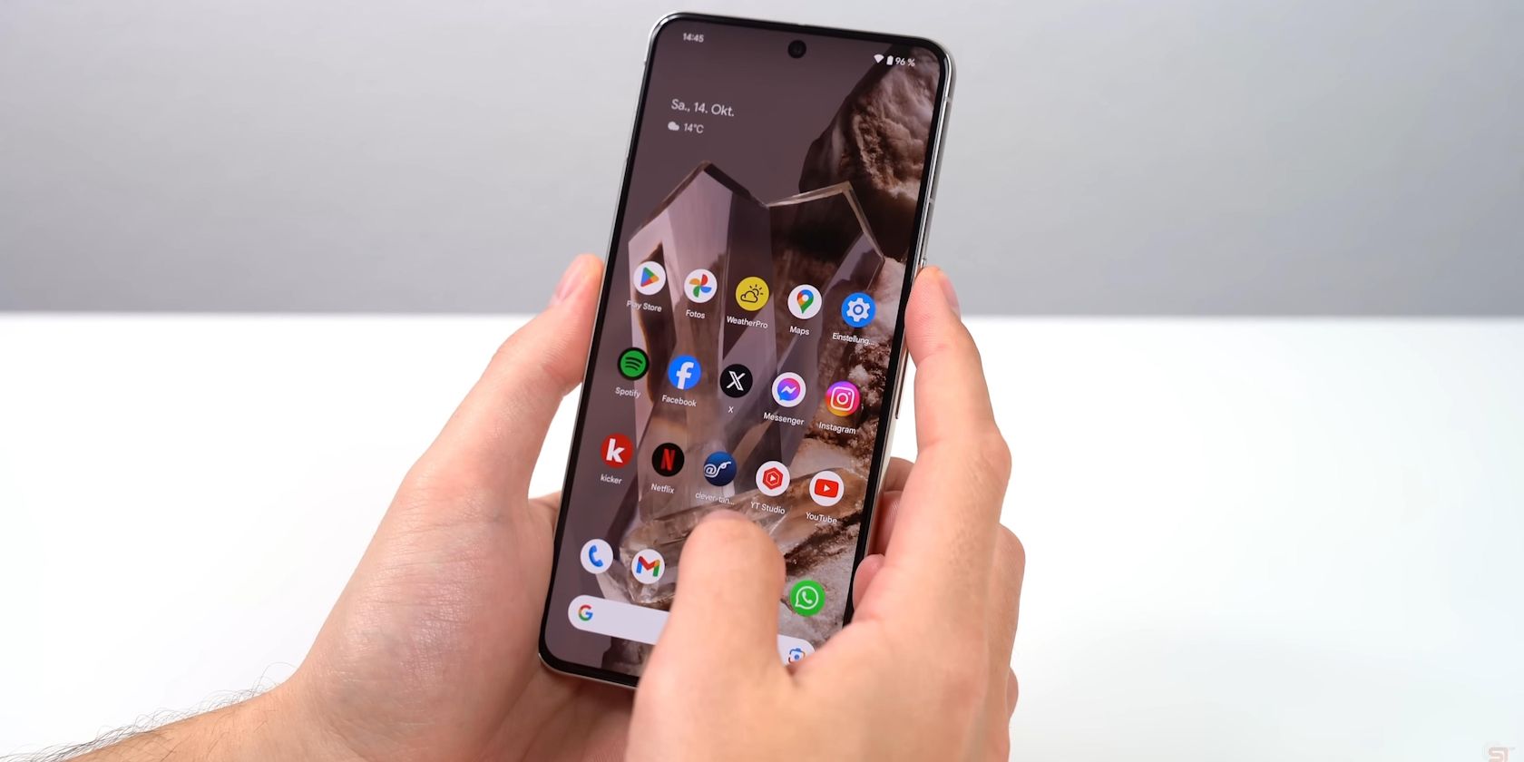 A guy holding a Google Pixel 8 showing apps
