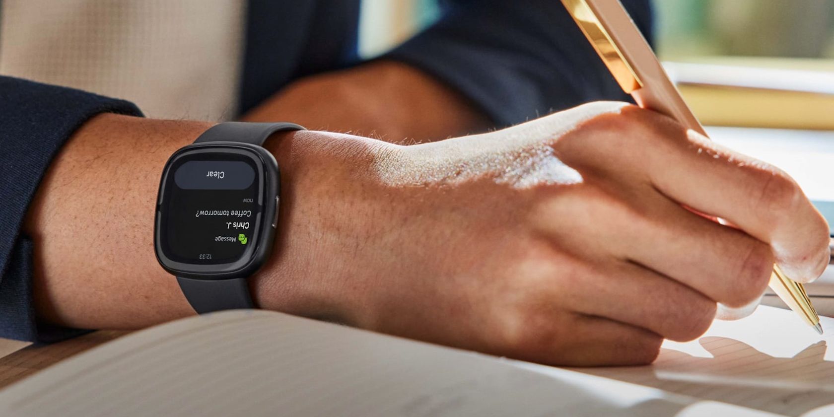 A guy taking notes wearing a Fitbit Sense 2