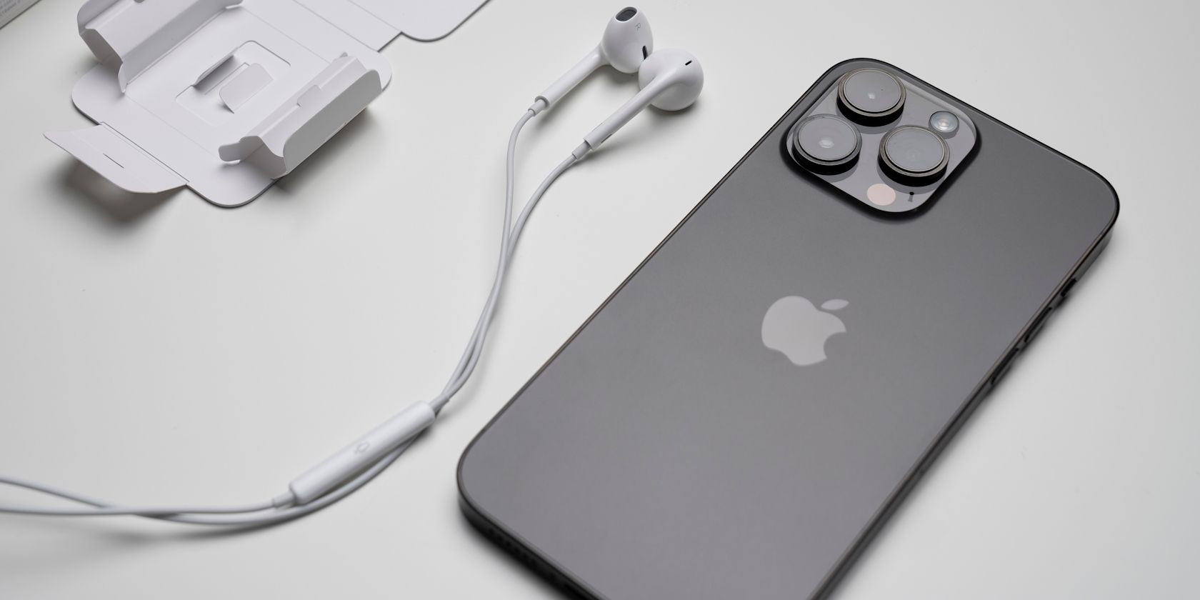 iPhone 14 Pro next to Apple EarPods on a desk