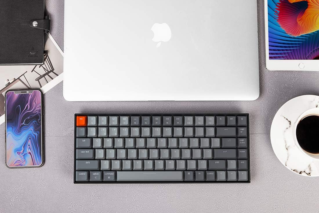 Keychron K2 Bluetooth Mechanical Keyboard on desk with smartphone, apple macbook, and tablet