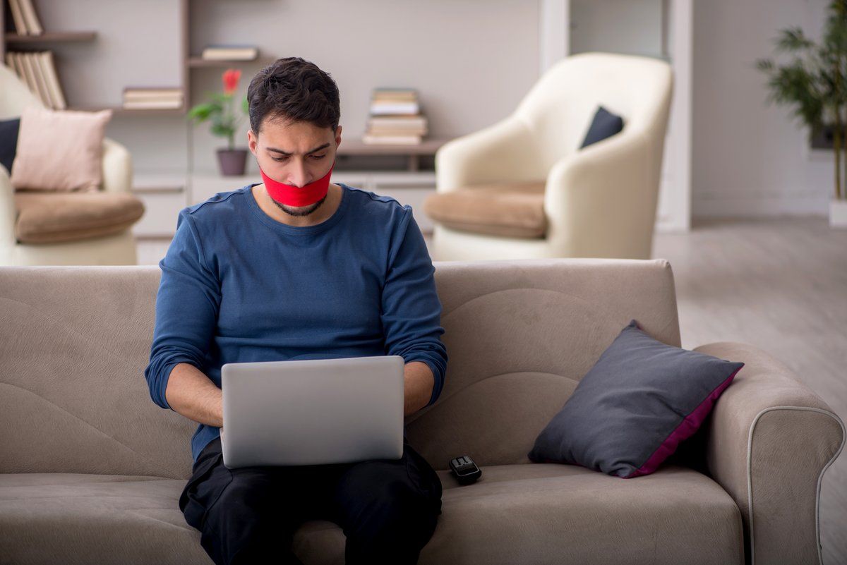 Man using computer mouth gagged