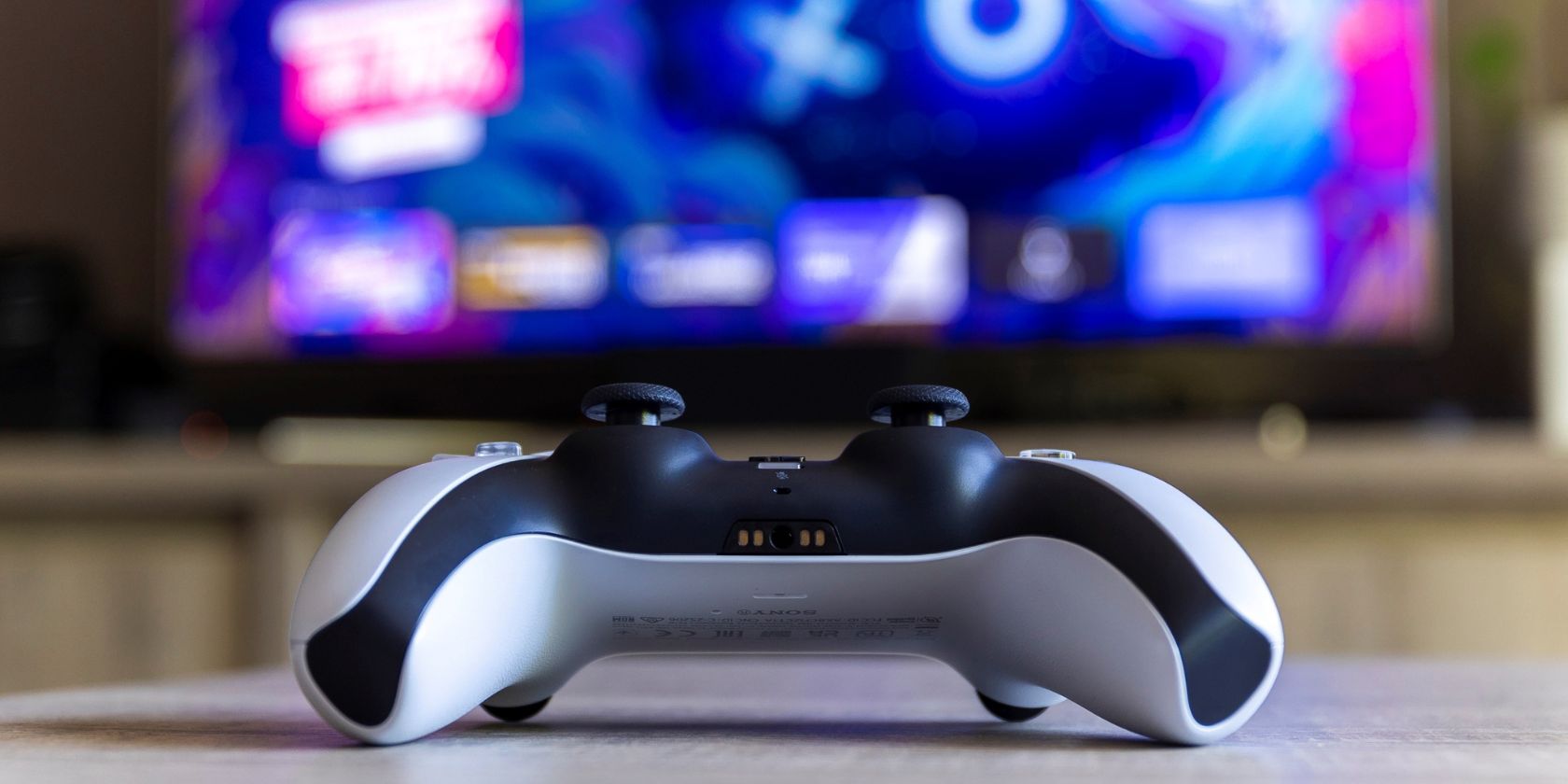 playstation 5 controller on a table with tv screen in the background