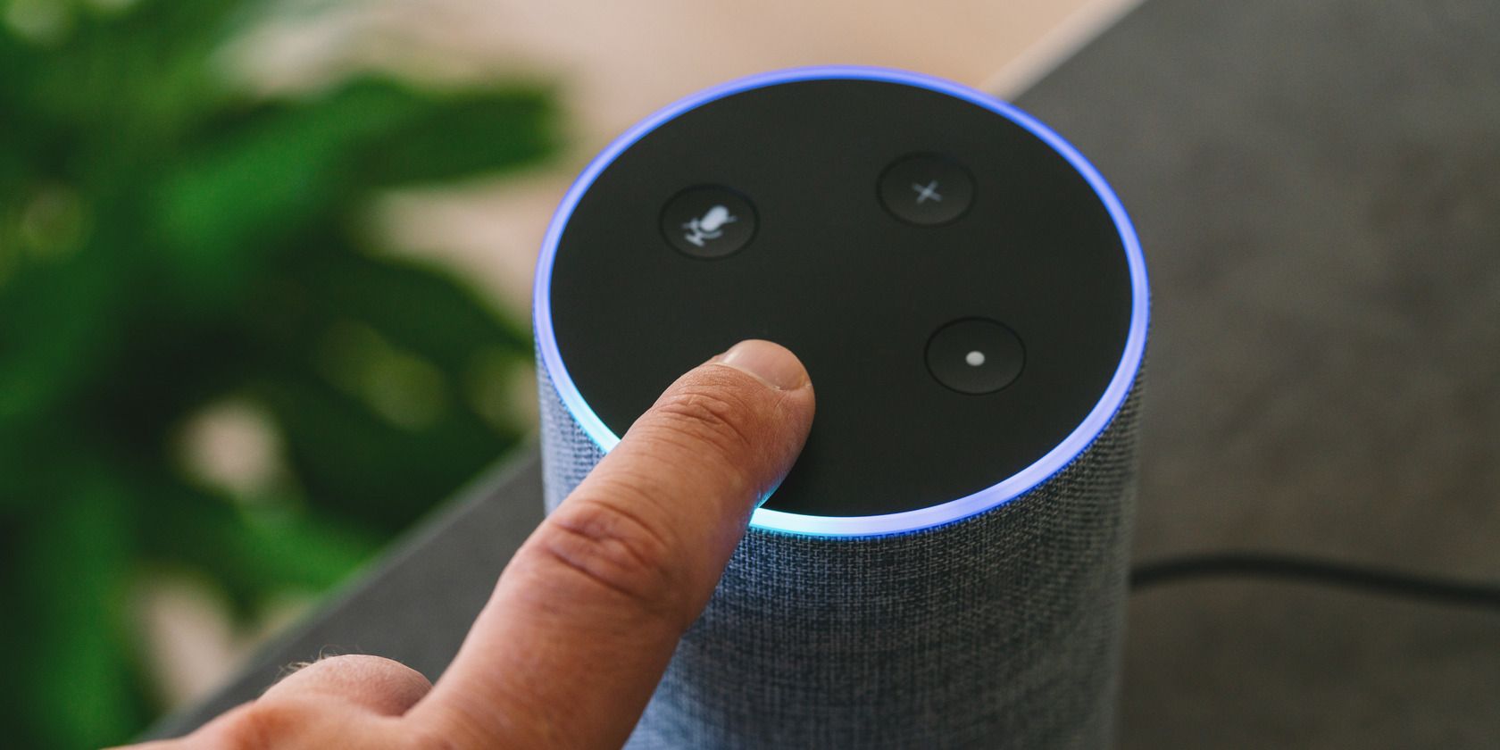 Amazon Echo smart speaker with a person's finger holding a button on the device
