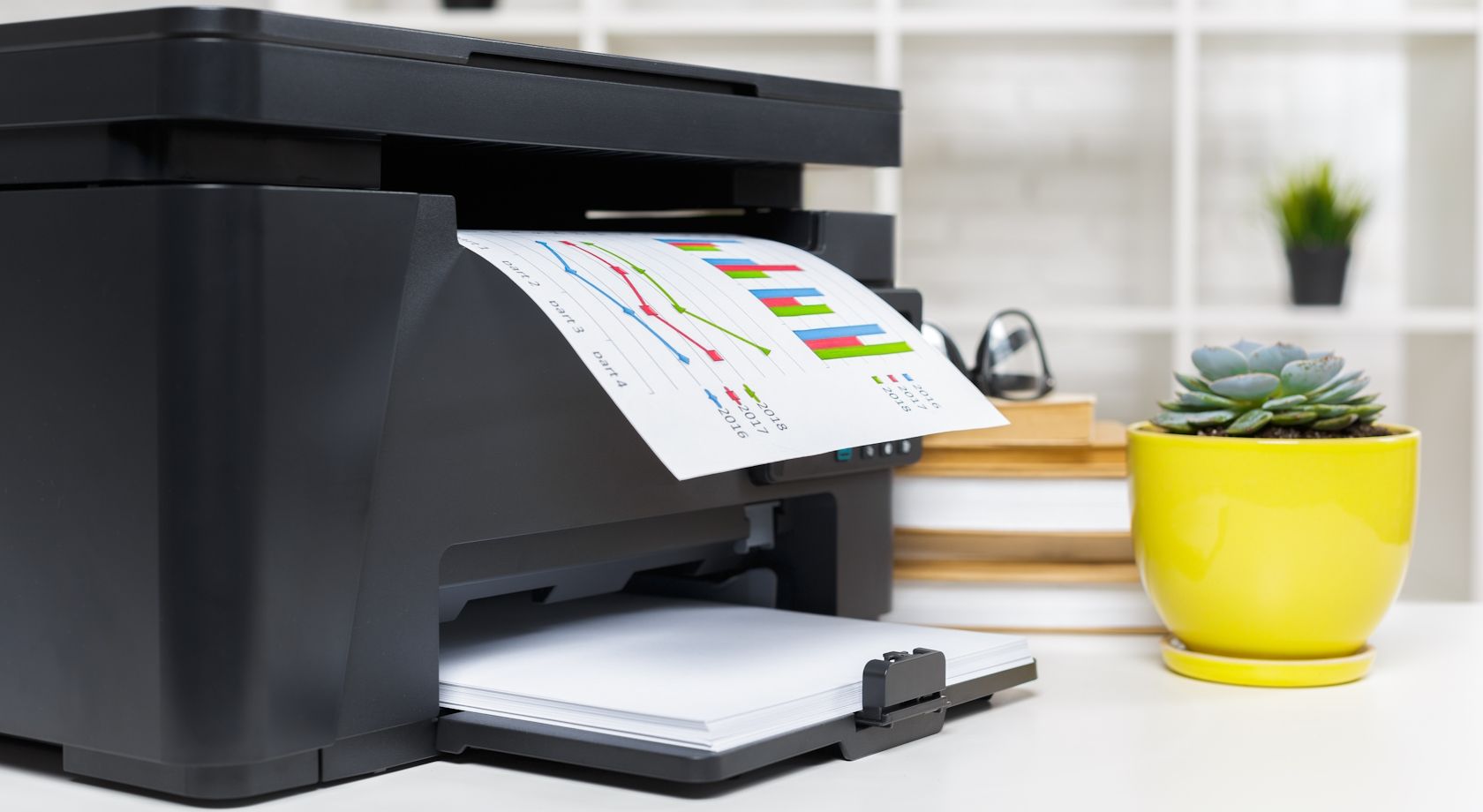 A printer on a desk printing out a document