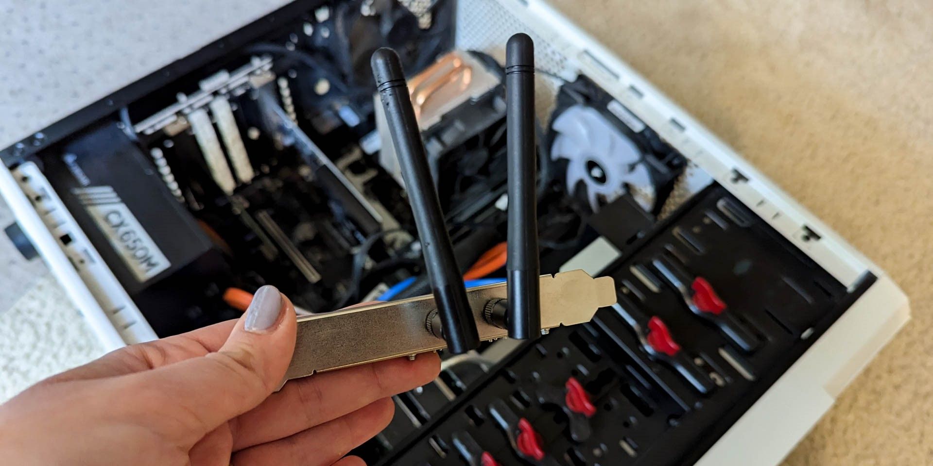 Person holding a TP Link Wifi Card above an open PC