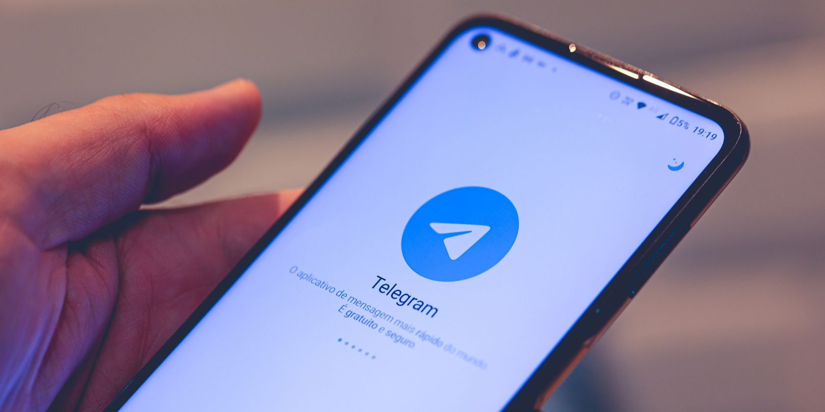 the telegram logo on a smartphone held in someone's hand