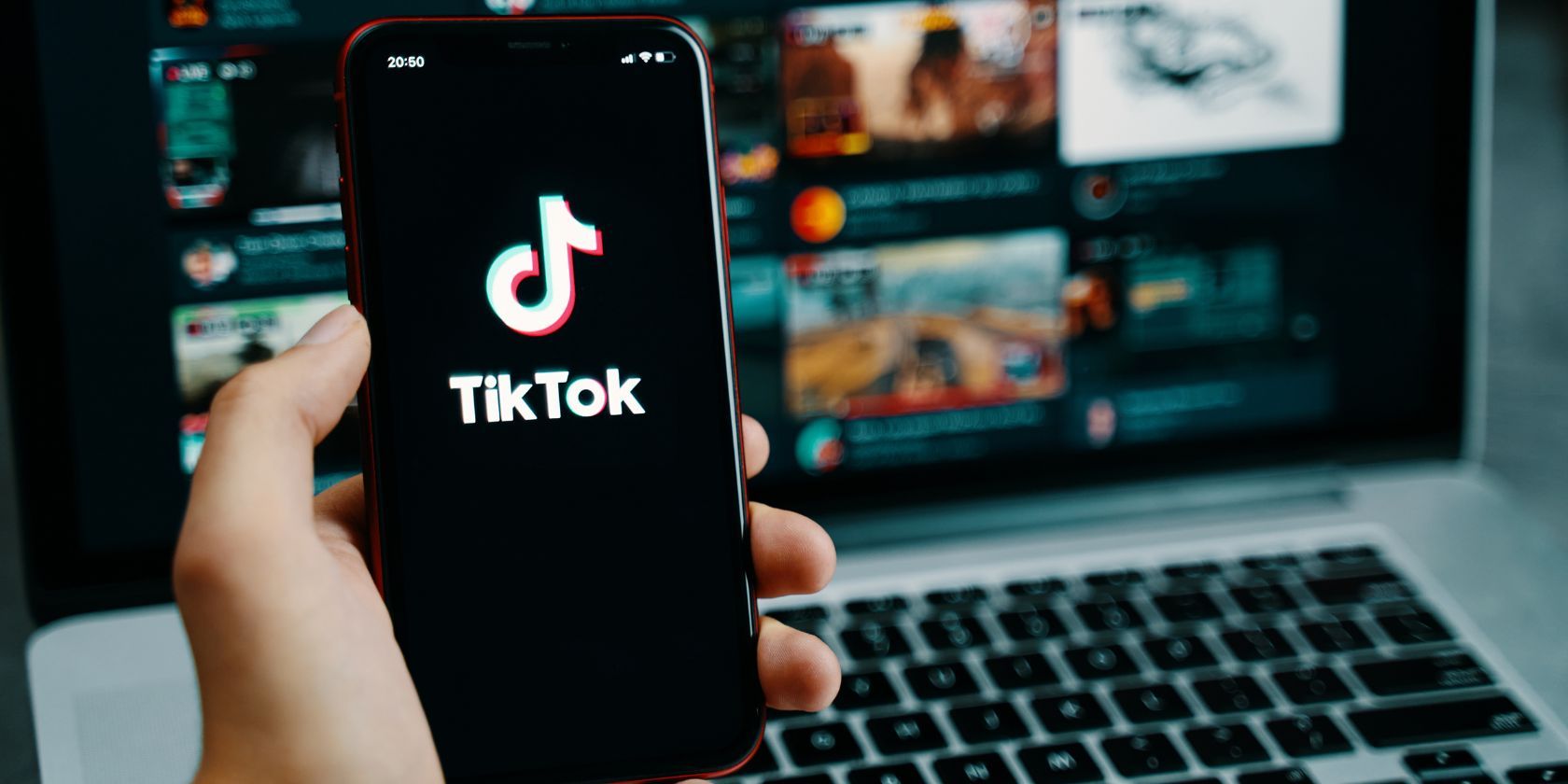 the tiktok logo on a smartphone in front of a laptop