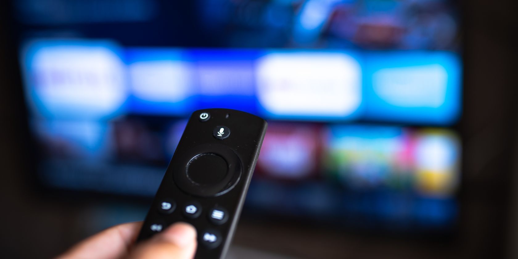 a hand holding a fire tv stick remote in front of a tv