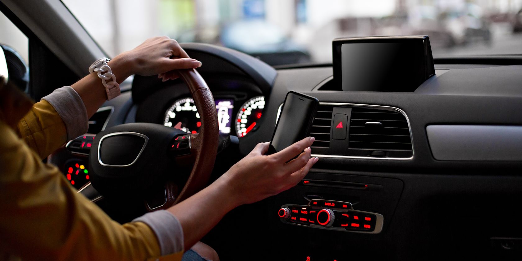 A man mounting a phone in his car while driving