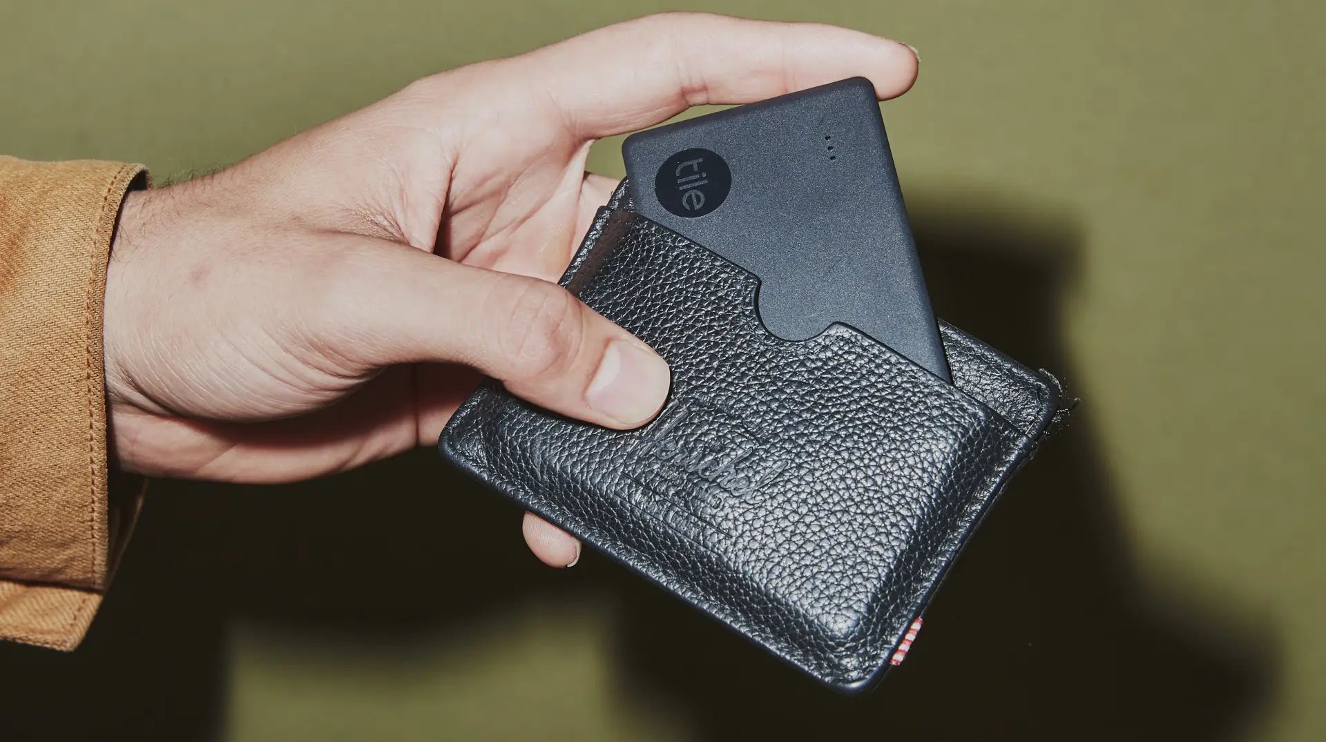 A man sliding a Tile Slim Bluetooth tracker into his wallet