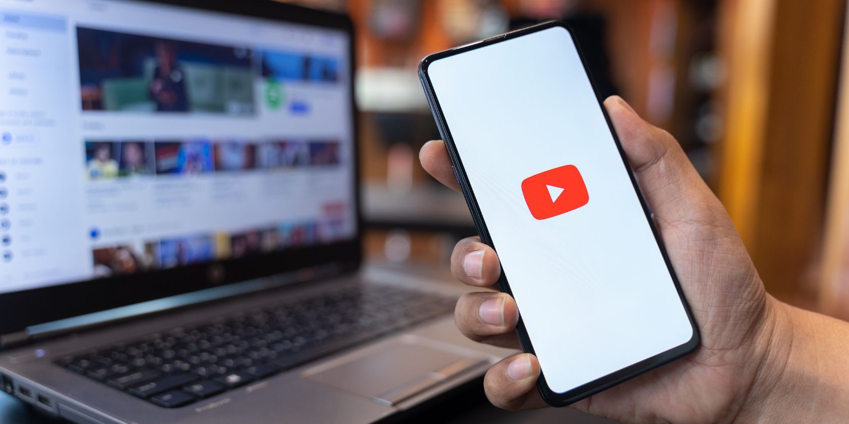 a person holding a phone with the youtube app and the youtube website in the background