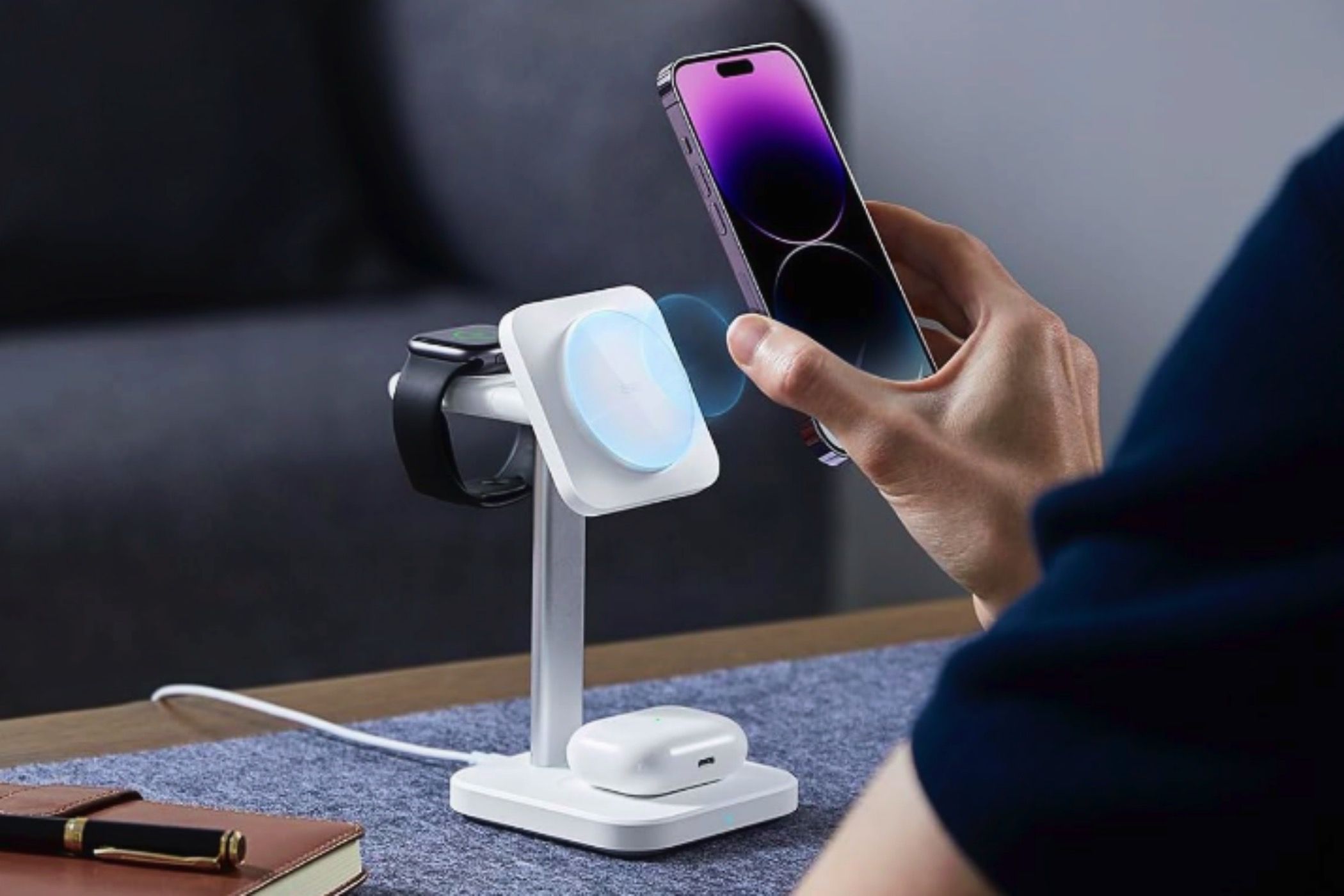 Um homem carregando um iPhone, AirPods e um Apple Watch em um conjunto de carregamento sem fio ESR HaloLock 3 em 1 Watch.