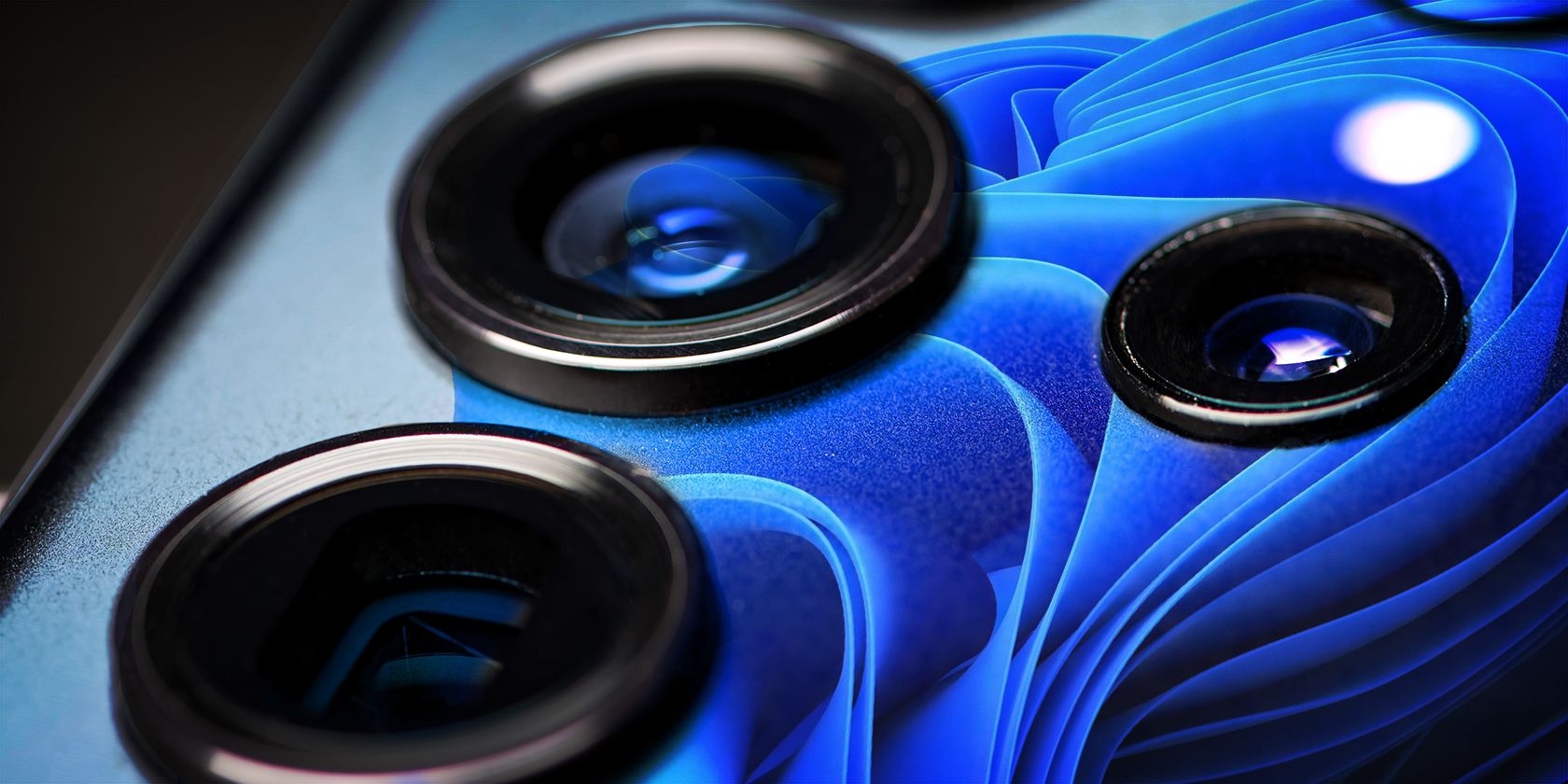 Close-up of a smartphone's camera, showcasing lens details with Windows 11 wallpaper.